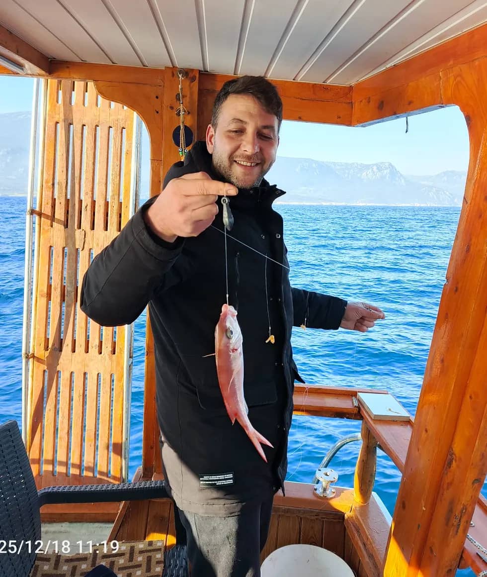 Okan Kaptan balık turunda yakalanan balığı gösteren misafir